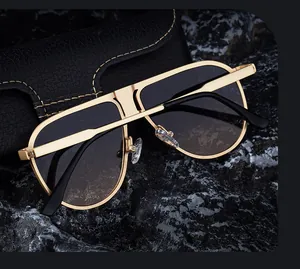 Detail of gold metal aviator sunglasses with gradient lenses on a black leather case