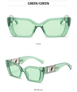 Detail of green cat-eye sunglasses featuring silver metal V-logo with rhinestone accents