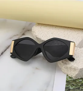 Close-up of oversized geometric sunglasses with black frame and golden metal hinge detail