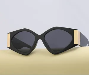 Detail of geometric black sunglasses with dark lenses and bold gold metal hinges