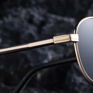 Detailopname van de gouden metalen scharnieren en zwarte pootjes op een aviator zonnebril