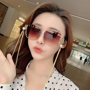 Details einer quadratischen Oversized-Sonnenbrille mit Verlaufsgläsern und Perlenkette
