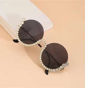 Detaillierte Nahaufnahme einer runden Oversize-Sonnenbrille mit Strass-Gold-Metallrahmen