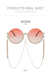 Detailansicht runder übergroßer orangefarbener Sonnenbrille mit Strass und Sternenkette