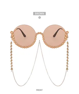 Detail einer runden Sonnenbrille mit braunen Gläsern, Strassrahmen und Sternenketten