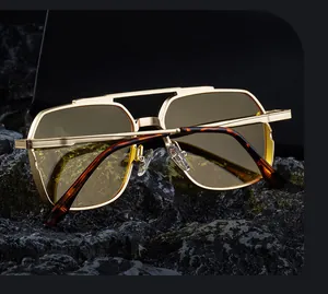 Detail of pilot sunglasses with gold double bridge frames and amber lenses on dark rock