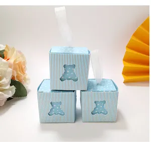 Three light blue candy boxes with bear cutout window and ribbon handle on white surface