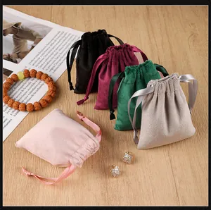 Detailed view of velvet drawstring jewelry pouches in multiple colors on a wooden surface