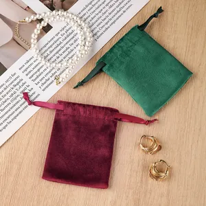 Velvet drawstring jewelry pouches with pearl necklace and gold earrings on desk