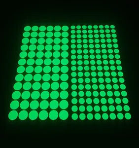 Luminous green dot wall stickers in two sizes glowing against a dark black background