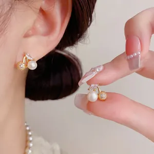 Detailed close-up of zircon pearl cherry earrings in elegant gold finish