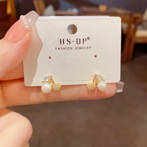 Detailed close-up of cherry stud earrings with white pearl and sparkling zircon stones