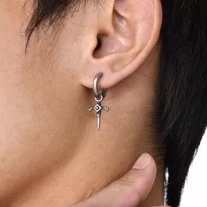 Close-up of a silver dagger pendant earring with a polished hoop on a model