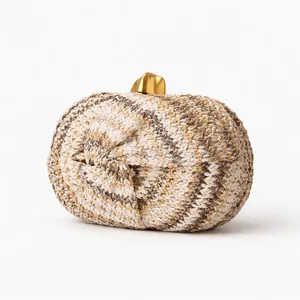 Detail of hand-woven straw clutch featuring textured weave and golden metal twist clasp
