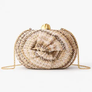 Detailed macro view of woven raffia evening bag with gold metal knot clasp and chain strap