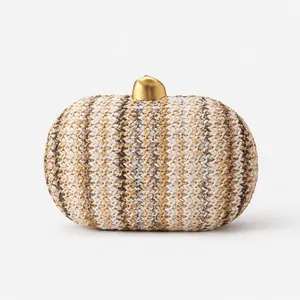Detail of the woven texture and irregular gold metal clasp on this straw clutch bag