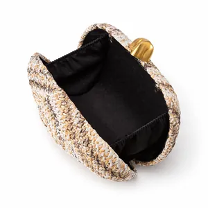 Detail of woven straw clutch bag with black lining and golden metal clasp closure