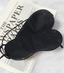 Close-up of soft black polyester sleep masks displayed in a wire basket on a plush rug