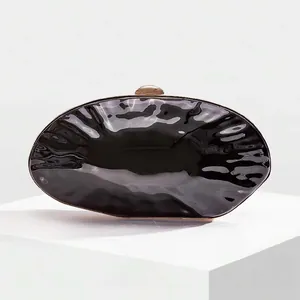 Close-up of black glossy shell evening clutch with elegant gold metal trim and clasp