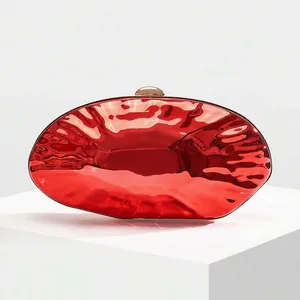 Detailed view of glossy red evening clutch bag with metallic finish and gold ball clasp