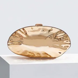 Close-up of golden evening clutch featuring water ripple texture and metallic buckle