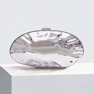 Detailed view of silver metallic shell clutch with wavy water ripple texture for party