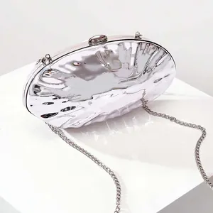 Close-up of a silver shell evening bag featuring a liquid metal ripple texture and chain