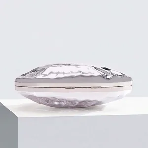 Detail of silver shell-shaped evening clutch with textured liquid metal wave design