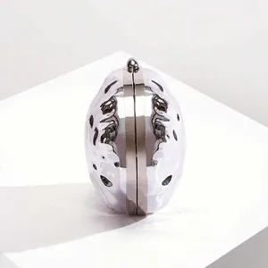 Detailed close-up of textured silver metallic shell evening bag on white pedestal