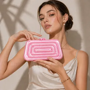 Pochette de soirée en acrylique rose avec texture à étages portée par un mannequin pour mariage