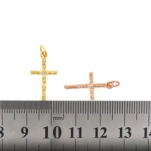 Gold plated cross pendant with zircon and textured surface on a white background