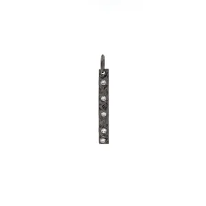 Detalle de un colgante rectangular negro texturizado con 5 circonitas incrustadas en blanco