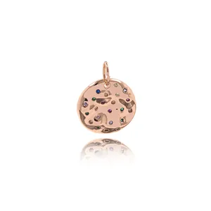 Detailed view of hammered gold round pendant with multi-colored gemstones and polished finish