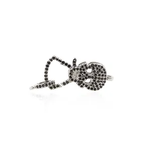 Detailed macro view of skull charm with black pave-set stones and 24K gold lobster clasp