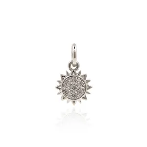Silver sun pendant with zirconia stones on white background with reflective surface