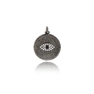 Detail of gunmetal evil eye charm with zircon stones and hammered metal texture