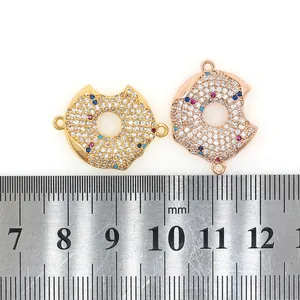 Detailed macro view of donut-shaped zircon connectors with 18K gold plating and scale ruler