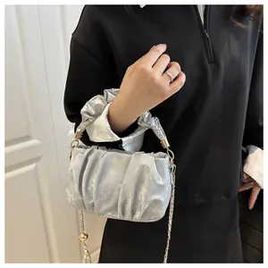 Silver pleated cloud bag with metallic finish and gold chain strap shown on model