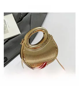 Détail du sac à main doré avec plis verticaux et poignée ronde découpée élégante