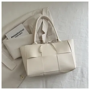Détail d'un sac cabas tressé blanc cassé avec de larges lanières et un nœud décoratif
