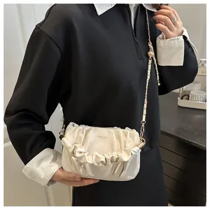 Close-up of cloud-pleated white crossbody bag with fine gold chain and logo detail