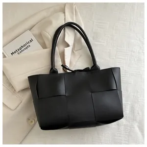 Détail du grand sac cabas noir tressé avec larges bandes en cuir et fermeture à nouer
