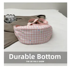 Detailed view of pink plaid crossbody bag with star prints and wear-resistant bottom