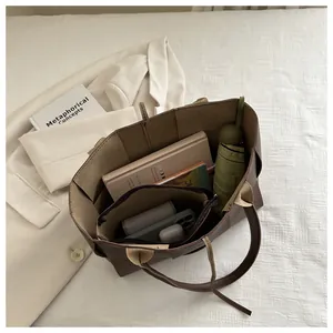 Vue de dessus d'un grand sac cabas marron avec pochette assortie et objets du quotidien