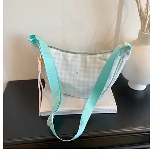 Detail of mint green plaid crescent bag with adjustable strap and colorful star patterns