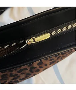 Détail du sac cabas léopard avec fermeture éclair dorée lisse et garniture en cuir noir