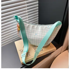 Detail of mint green gingham half-moon bag with star prints and acrylic chain accessory