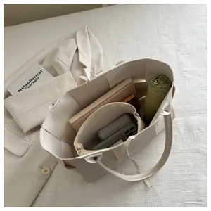Vue de dessus d'un grand cabas tressé crème montrant le rangement pour livres et parapluie