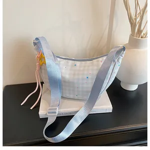 Detail of blue plaid crescent bag with star patterns and wide strap on white books