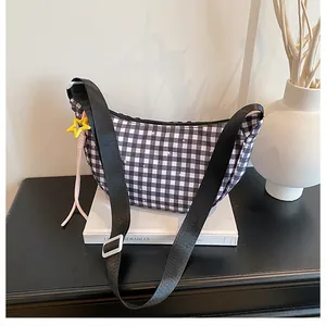 Detail of checkered crescent bag with star pattern, yellow charm and wide strap